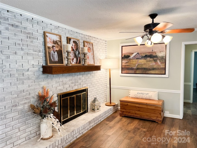 sitting room with a textured ceiling, a brick fireplace, hardwood / wood-style floors, and ceiling fan