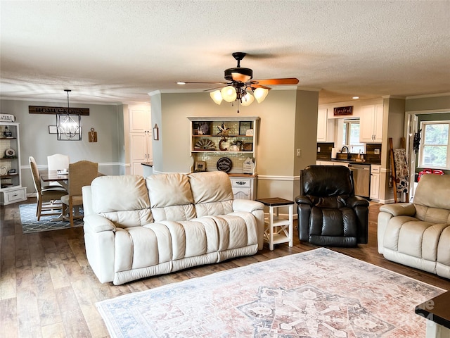 living room featuring hardwood / wood-style floors, ceiling fan, ornamental molding, and a textured ceiling