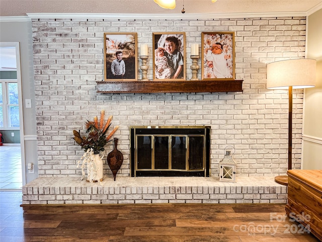 details featuring hardwood / wood-style floors, a textured ceiling, crown molding, and a brick fireplace