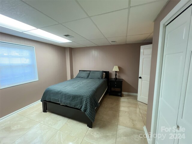 bedroom with a paneled ceiling and light tile patterned floors