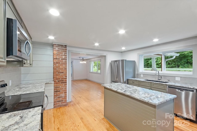 kitchen featuring light wood-style floors, tasteful backsplash, stainless steel appliances, and a sink