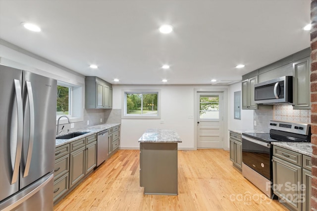 kitchen featuring stainless steel appliances, light wood-type flooring, a center island, and a sink