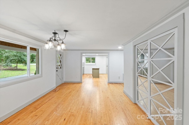 unfurnished dining area featuring baseboards, plenty of natural light, light wood-style flooring, and crown molding