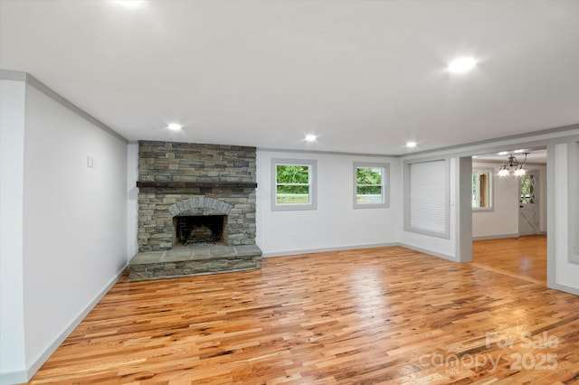 unfurnished living room with recessed lighting, baseboards, wood finished floors, and a stone fireplace