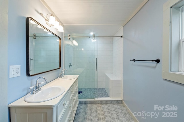 bathroom with a stall shower, a sink, baseboards, and double vanity