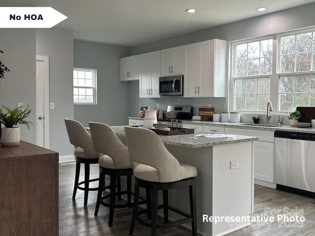 kitchen with white cabinets, a center island, sink, and appliances with stainless steel finishes