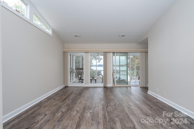 empty room with plenty of natural light and dark wood-type flooring