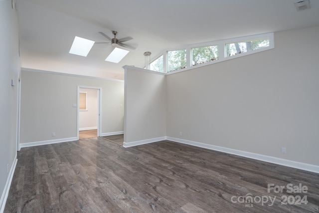 spare room featuring dark hardwood / wood-style flooring, vaulted ceiling with skylight, and ceiling fan