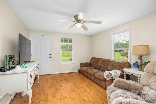 living room featuring ceiling fan, plenty of natural light, and light hardwood / wood-style floors