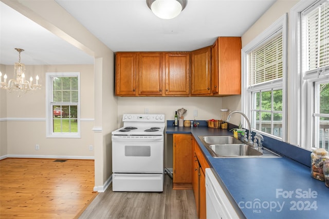 kitchen with white appliances, a wealth of natural light, sink, and a notable chandelier