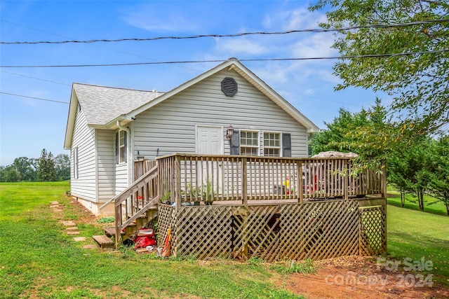 back of property featuring a deck and a lawn