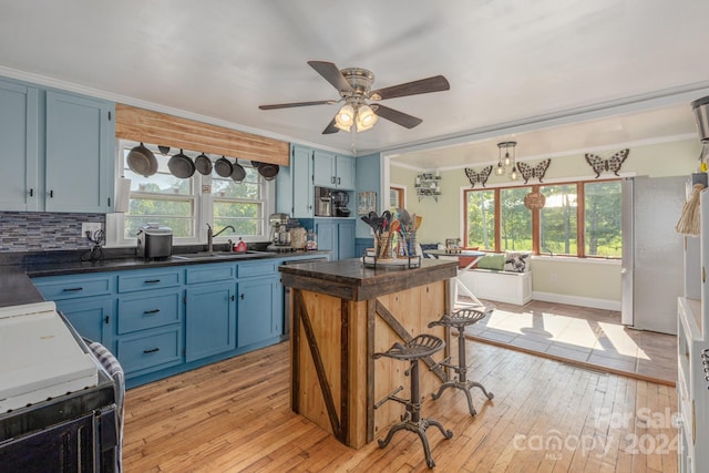 kitchen with blue cabinets, light hardwood / wood-style flooring, sink, and ceiling fan