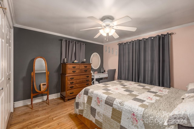 bedroom with ceiling fan, light wood-type flooring, crown molding, and a closet