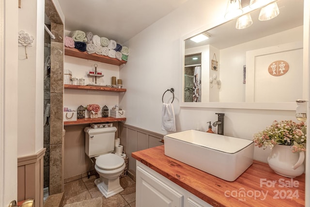 bathroom featuring curtained shower, vanity, toilet, and tile patterned floors