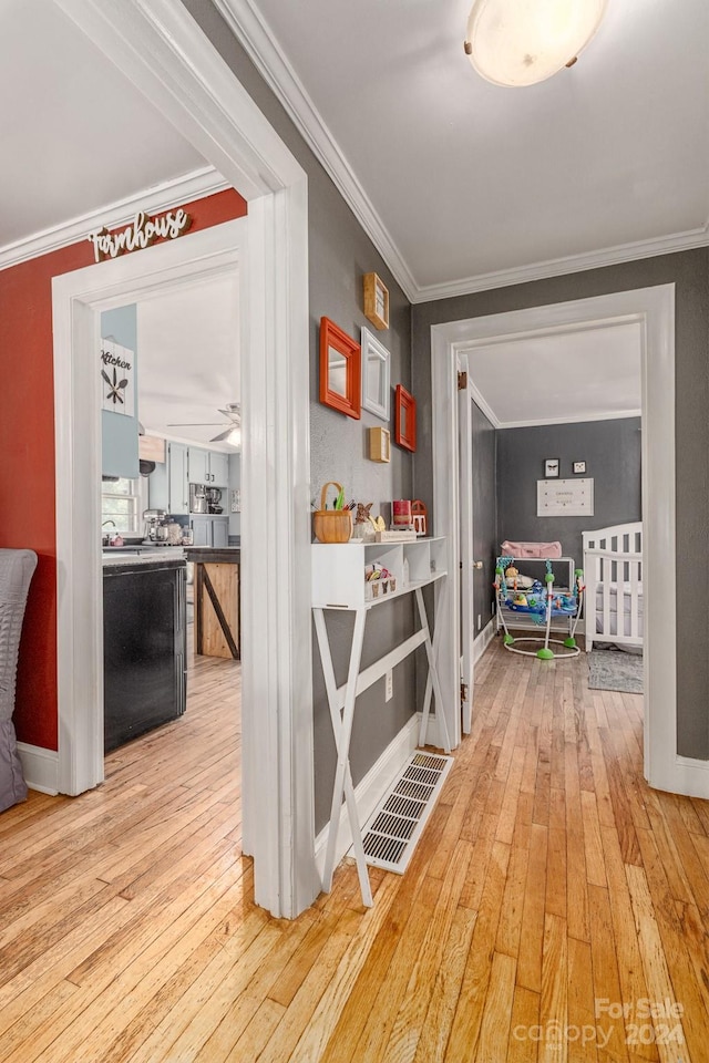 hallway featuring light wood finished floors, baseboards, and ornamental molding