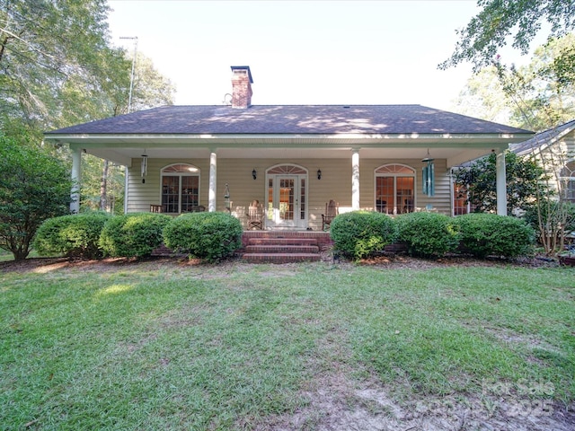 view of front of home with covered porch, a chimney, and a front lawn