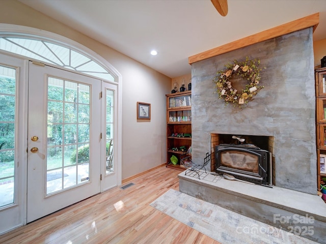 interior space with baseboards, visible vents, a wood stove, light wood-style floors, and recessed lighting