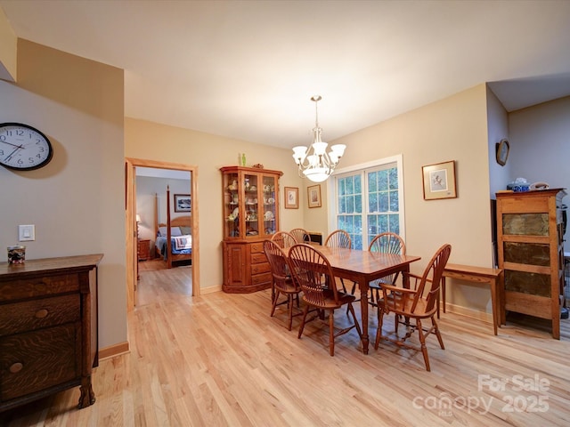 dining room with baseboards, light wood-type flooring, and an inviting chandelier