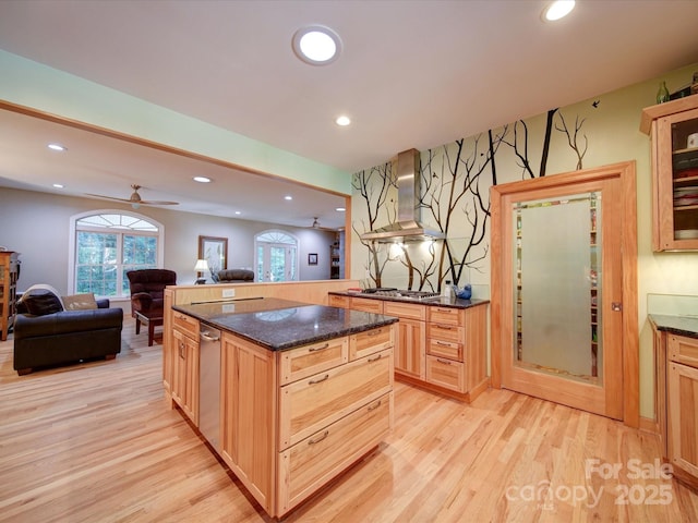 kitchen featuring recessed lighting, light wood-style flooring, open floor plan, dark stone countertops, and wall chimney exhaust hood