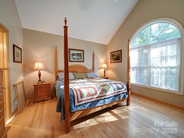 bedroom with multiple windows, vaulted ceiling, light wood-style flooring, and baseboards