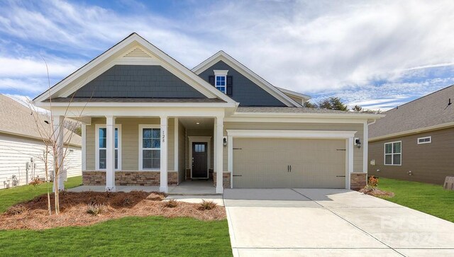 craftsman inspired home with a front lawn, a porch, and a garage