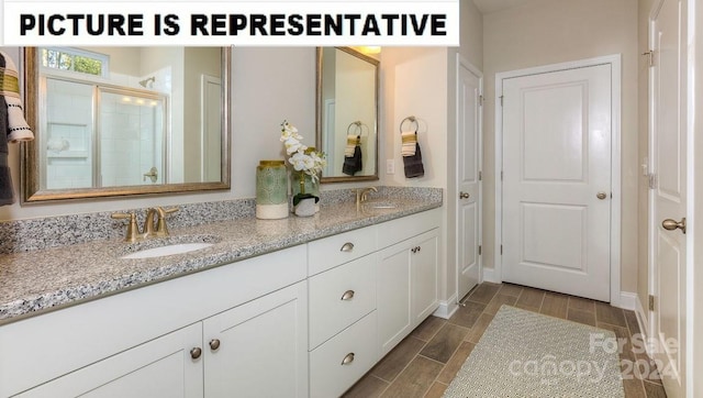 bathroom featuring a shower with door and vanity