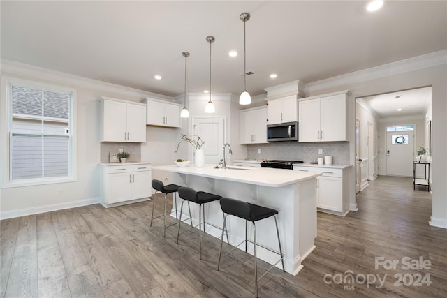 kitchen with light wood-type flooring, white cabinetry, and a kitchen island with sink