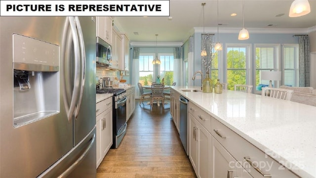 kitchen featuring hanging light fixtures, crown molding, appliances with stainless steel finishes, and sink