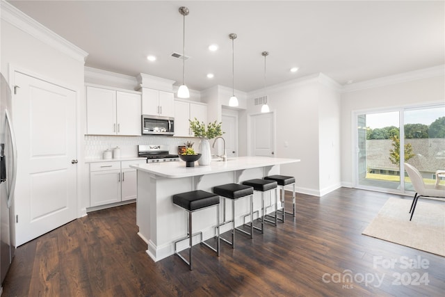 kitchen with stainless steel appliances, dark wood-type flooring, white cabinets, a kitchen island with sink, and pendant lighting