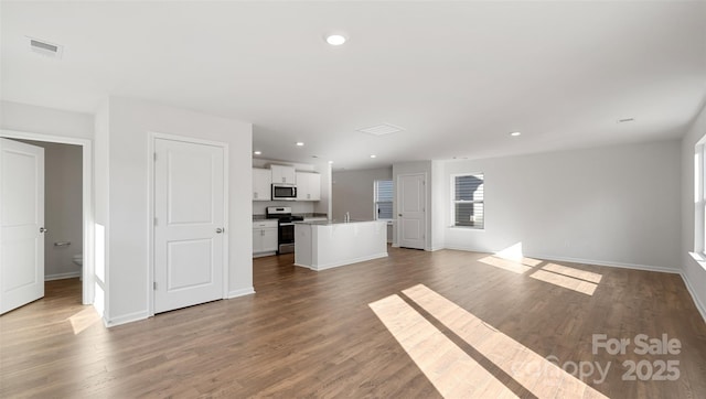 unfurnished living room featuring a wealth of natural light, visible vents, recessed lighting, and wood finished floors