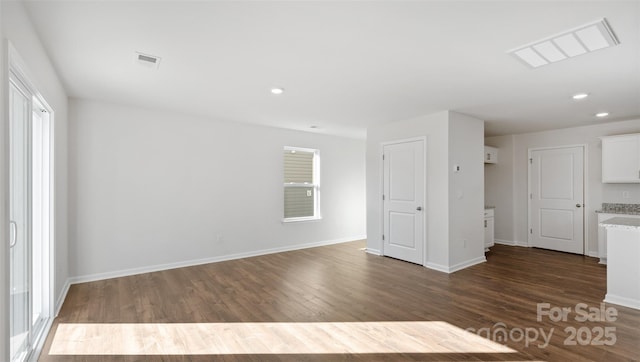 unfurnished room featuring baseboards, dark wood-style flooring, visible vents, and a healthy amount of sunlight