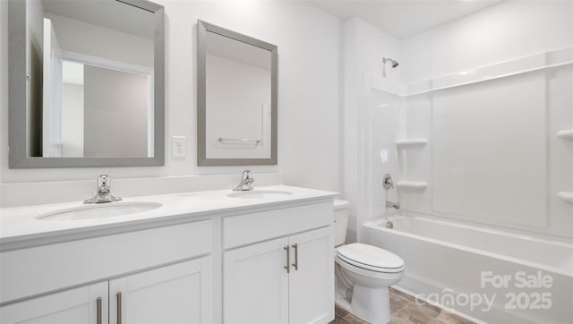 bathroom with double vanity, tub / shower combination, a sink, and toilet