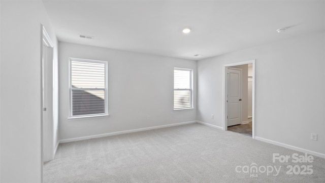 carpeted empty room with visible vents and baseboards