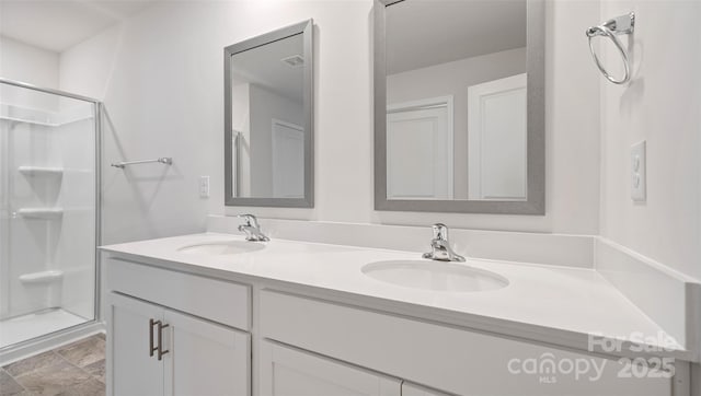 bathroom featuring double vanity, a stall shower, and a sink