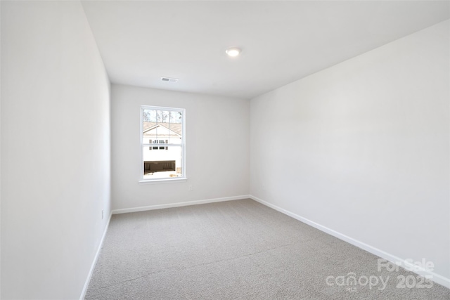 spare room with carpet floors, visible vents, and baseboards