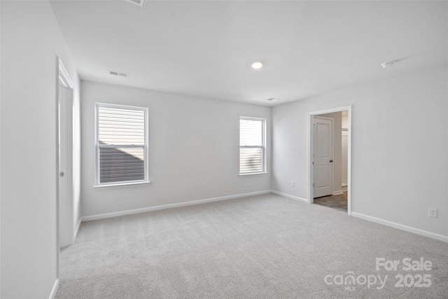 carpeted spare room with visible vents and baseboards