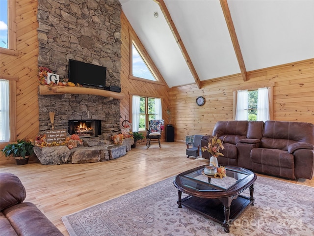 living room featuring beam ceiling, high vaulted ceiling, a fireplace, hardwood / wood-style floors, and wood walls