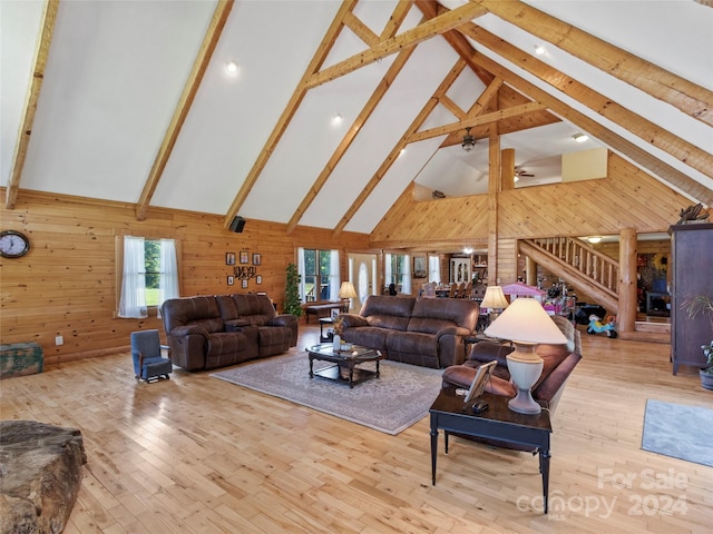 living room featuring wooden walls, beamed ceiling, high vaulted ceiling, and light wood-type flooring