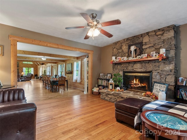 living room featuring a stone fireplace, a wealth of natural light, and light hardwood / wood-style flooring