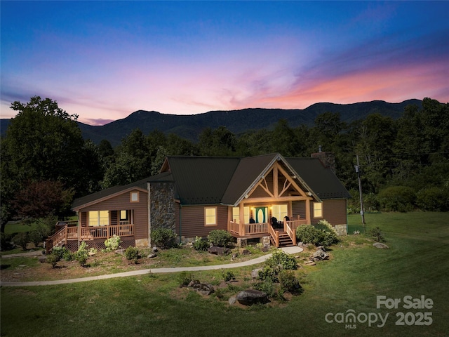 view of front of home featuring a chimney, a deck with mountain view, and a front lawn