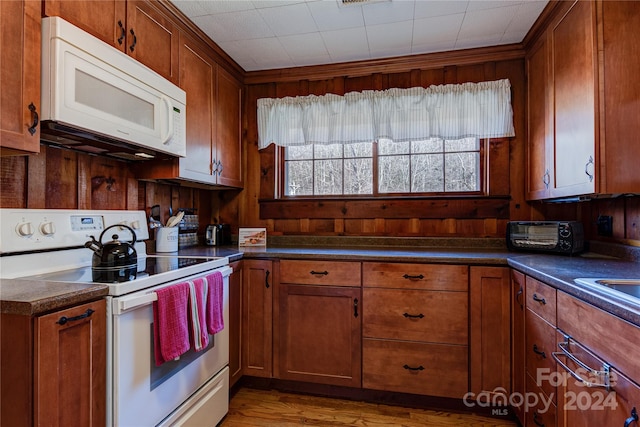 kitchen featuring light wood-type flooring, white appliances, and wood walls