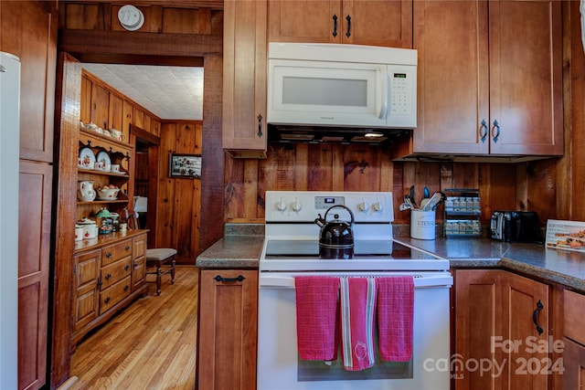 kitchen featuring light hardwood / wood-style flooring, wooden walls, and white appliances