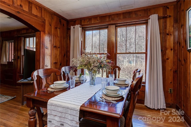 dining room featuring wood-type flooring, wood walls, and crown molding