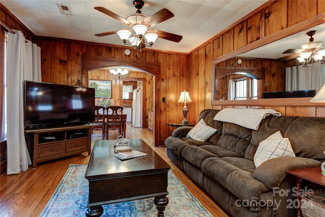 living room with wooden walls, light hardwood / wood-style floors, a healthy amount of sunlight, and crown molding