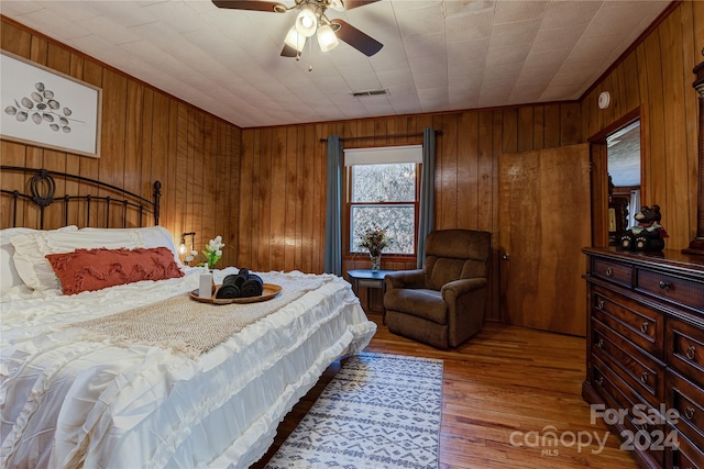 bedroom with wood walls, ceiling fan, and hardwood / wood-style flooring