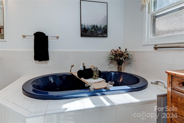 bathroom with tiled tub and vanity