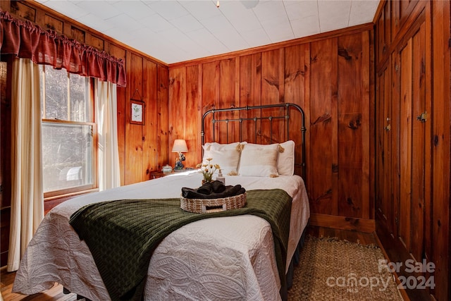 bedroom with wood-type flooring, wood walls, and crown molding