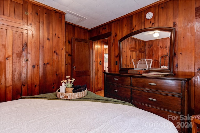 bedroom featuring ornamental molding and wooden walls