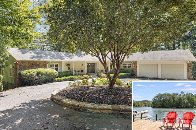 ranch-style home with a garage and a water view