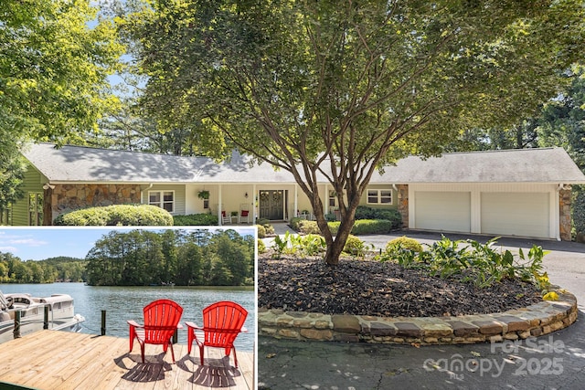 view of front of home with stone siding, driveway, a water view, a garage, and a shingled roof